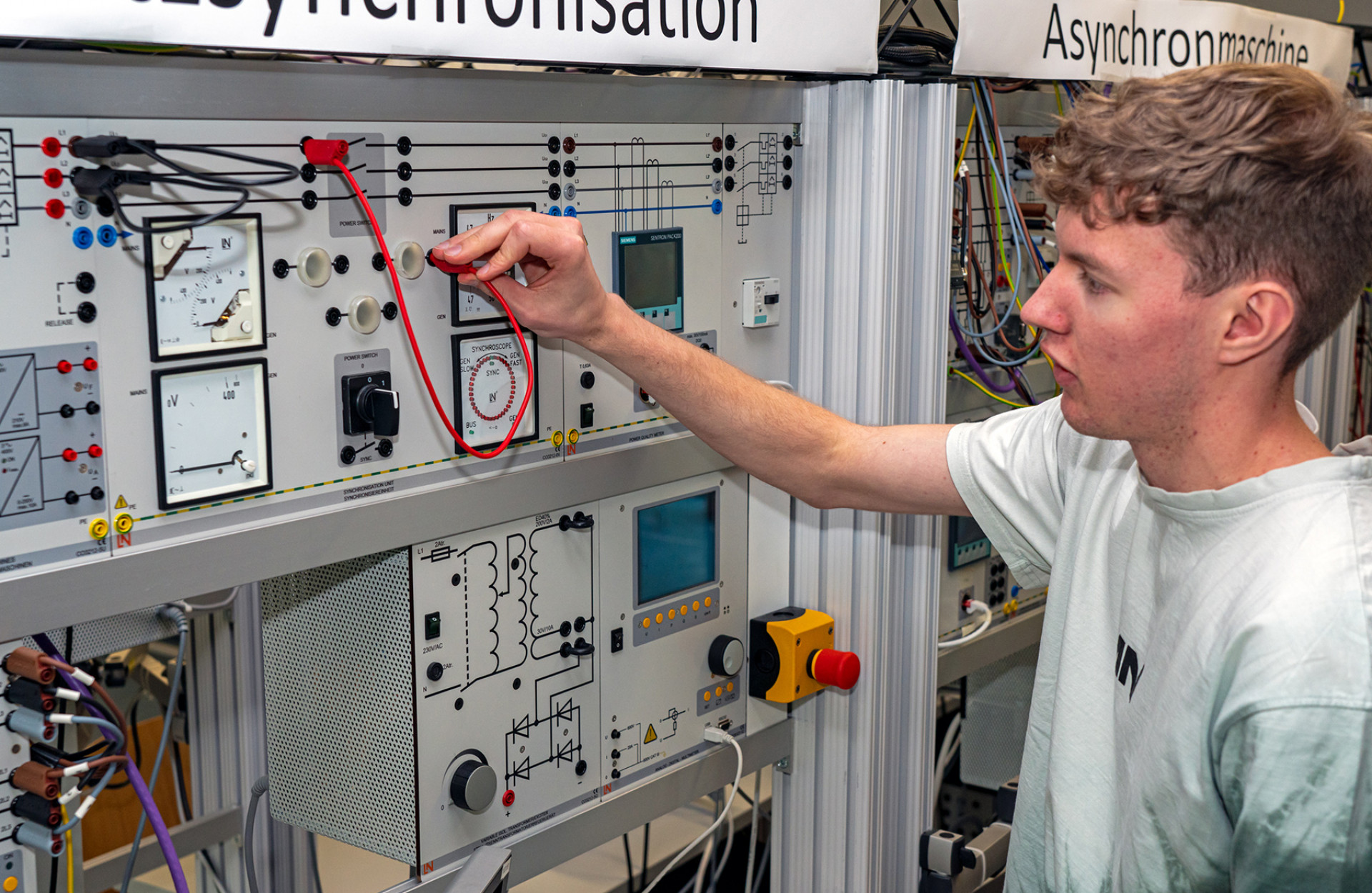 Studierender Jens Hagmeyer steht vor Modell Netzsynchronisation im Labor für Elektrische Systeme